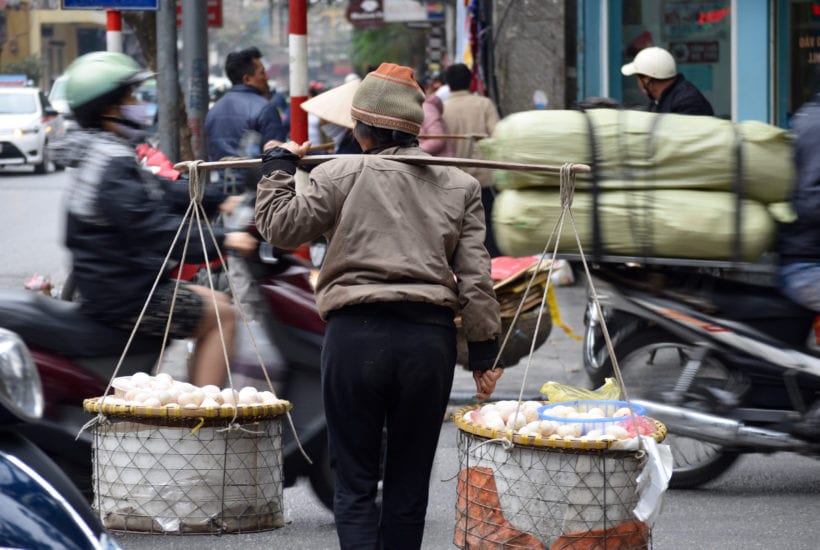 A street vendor crosses a busy avenue in Hanoi © | Nikki Vargas