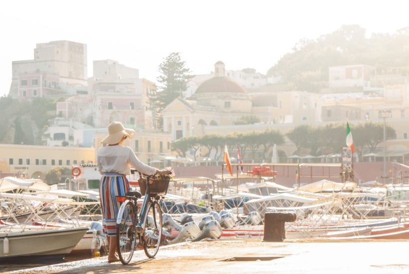 Young woman with bike at Ponza Island harbor pier in Italy | © WineDonuts/Shutterstock